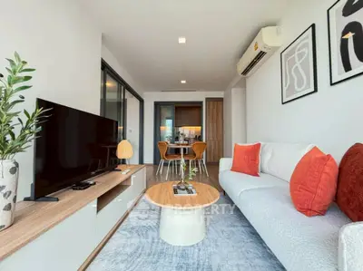 Modern living room with stylish decor and open layout, featuring a cozy sofa and large TV.