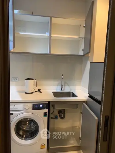 Compact kitchen with washing machine and modern appliances in a cozy apartment.