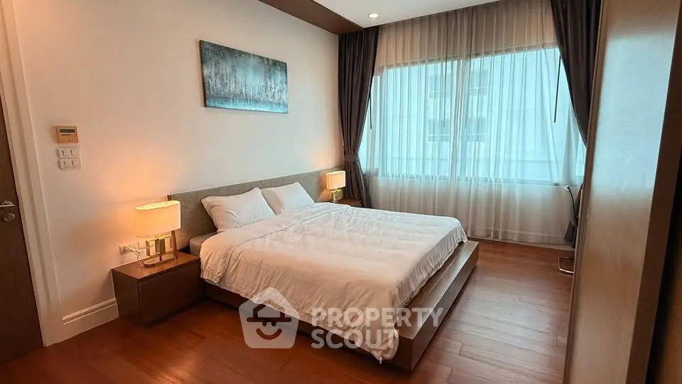 Spacious bedroom with modern decor and large window offering natural light.