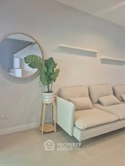 Modern living room with stylish beige sofa and decorative mirror, perfect for cozy relaxation.