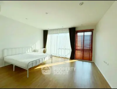 Spacious bedroom with natural light and wooden flooring