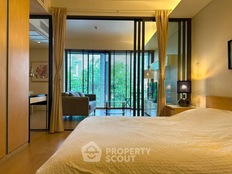 Modern bedroom with sliding glass doors leading to a stylish living room and balcony view.