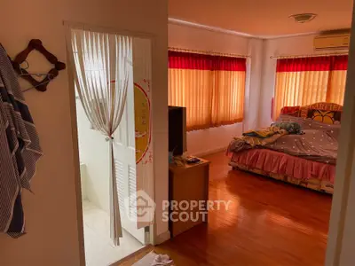 Cozy bedroom with wooden flooring and natural light, featuring a comfortable bed and stylish decor.