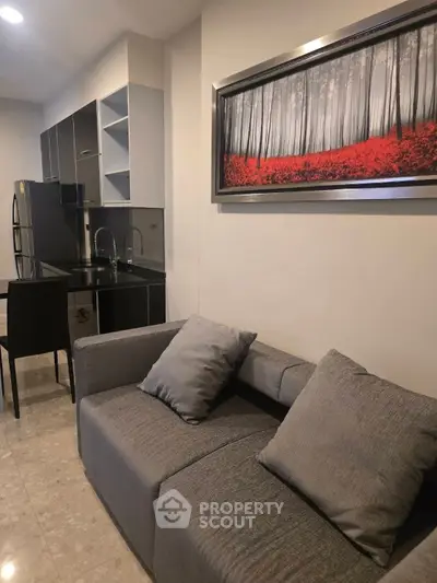 Modern living room with sleek kitchen, stylish sofa, and elegant wall art in a contemporary apartment.