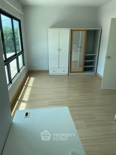 Spacious bedroom with large window and ample storage space