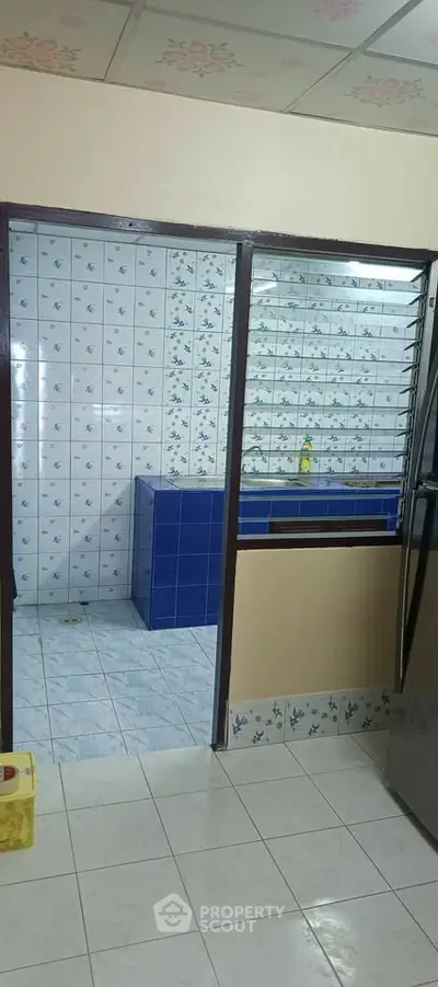 Charming kitchen with blue and white tiled walls and stainless steel appliances.