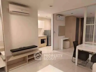 Modern open-plan living area with sleek kitchen and dining space, featuring air conditioning and stylish furnishings.