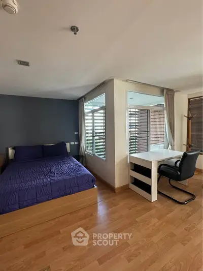 Spacious bedroom with modern decor and natural light, featuring a cozy bed and a stylish desk area.
