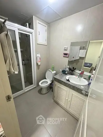 Modern bathroom with shower, toilet, and vanity in a sleek real estate property.