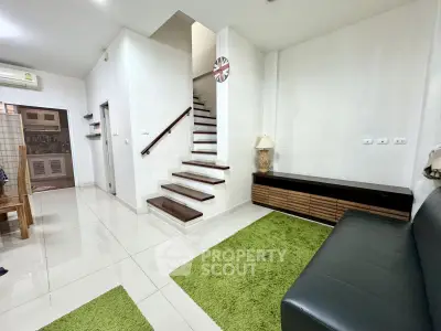 Modern living room with sleek staircase and green accents