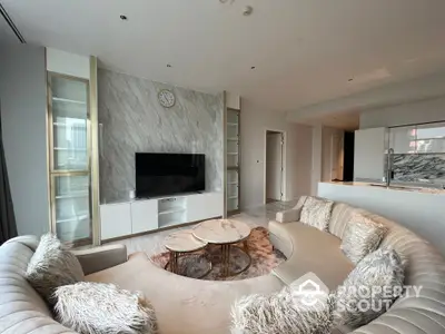 Luxurious living room with marble wall accents, modern circular sofa, and sleek entertainment unit, bathed in natural light from floor-to-ceiling windows.