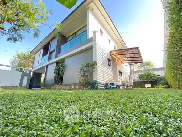 Modern two-story house with lush green lawn and spacious outdoor area.