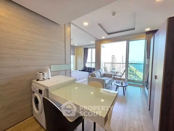 Modern open-plan living room with kitchen and balcony offering stunning city views.