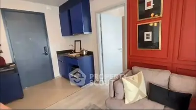 Modern studio apartment with stylish blue kitchenette and cozy living area.