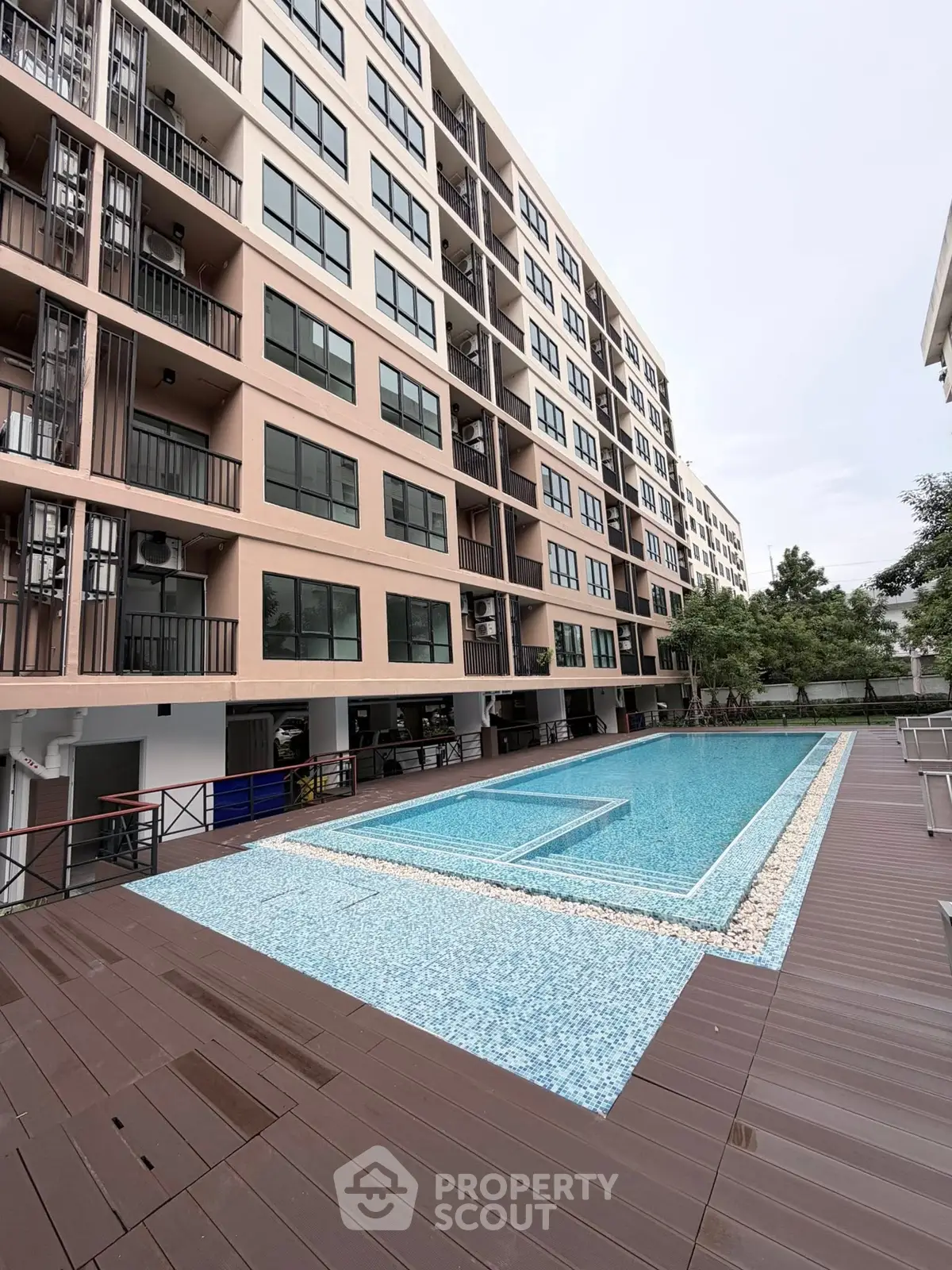 Modern apartment building with a stylish swimming pool and spacious deck area.