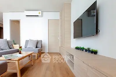 Modern living room with sleek wooden flooring, stylish furniture, and wall-mounted TV.