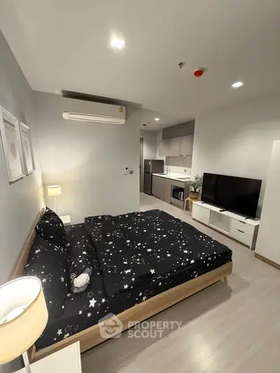 Modern studio apartment with cozy bedroom and compact kitchen area, ideal for urban living.