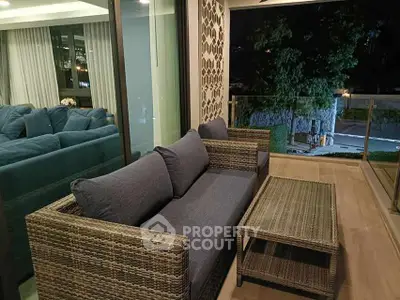 Stylish balcony with wicker furniture and glass railing offering a serene night view.