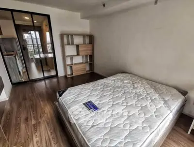 Spacious bedroom with wooden flooring and modern glass partition leading to kitchen.
