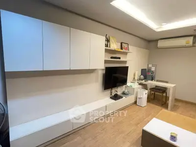 Modern living room with sleek white cabinets and wall-mounted TV, featuring stylish wooden flooring and ambient lighting.