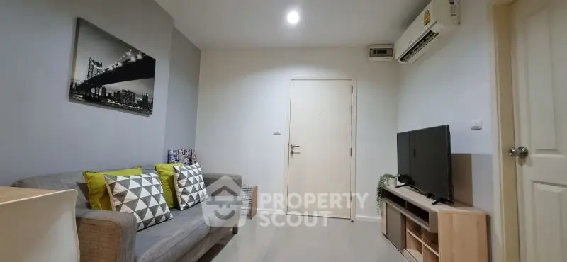 Modern living room with stylish decor, featuring a cozy sofa, air conditioning, and a sleek TV setup.