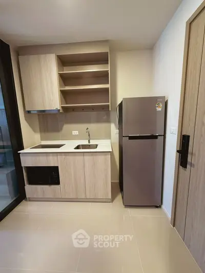 Modern kitchen with sleek cabinetry and stainless steel fridge in a compact layout.