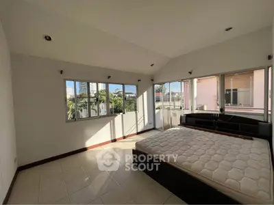 Spacious bedroom with large windows and natural light in modern apartment.