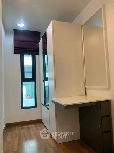 Modern study room with sleek design and ample natural light, featuring wooden flooring and built-in storage.