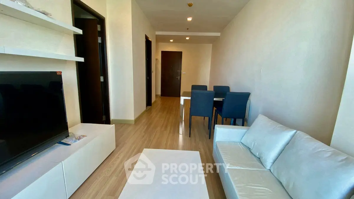 Modern living room with sleek furniture and dining area in open layout apartment.