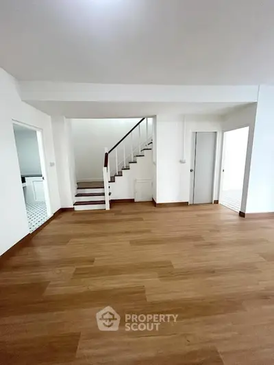 Spacious modern interior with wooden flooring and staircase, ideal for family living.
