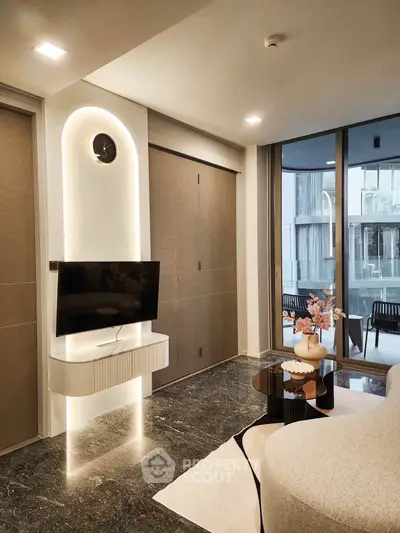 Modern living room with sleek TV setup and stylish decor, featuring large windows and elegant furniture.