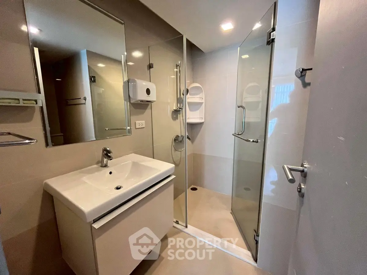 Modern bathroom with glass shower and sleek vanity in contemporary design.