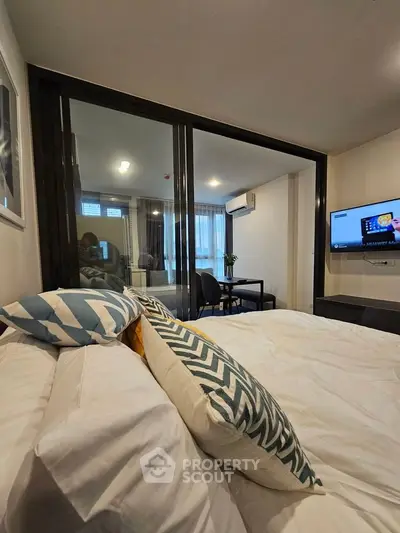 Modern bedroom with stylish decor and sliding glass doors leading to a cozy study area.