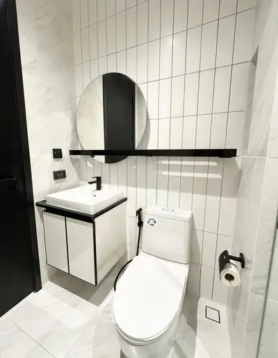 Modern bathroom with sleek design, featuring a round mirror and compact sink.