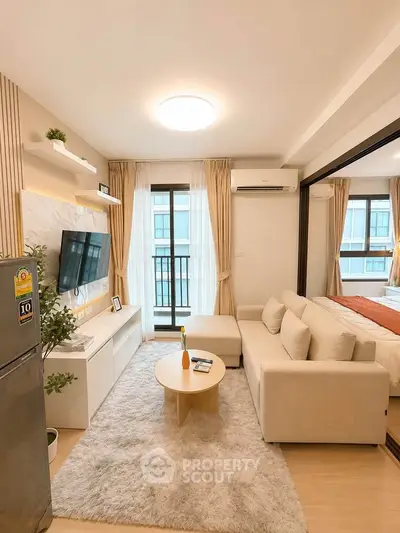 Modern living room with cozy beige sofa, wall-mounted TV, and large window with city view.