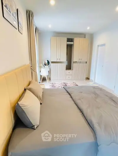 Spacious bedroom with modern decor and ample natural light, featuring a stylish wardrobe and cozy bedding.