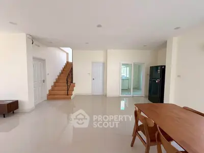 Spacious open-plan living area with modern dining set and staircase, ideal for family gatherings.