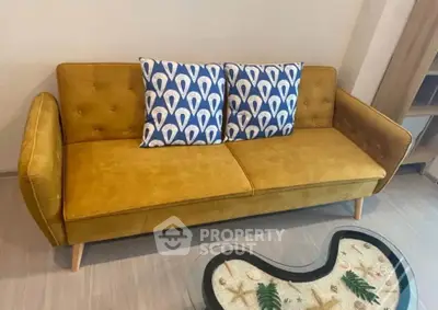 Stylish mustard yellow sofa with patterned cushions in modern living room setting.