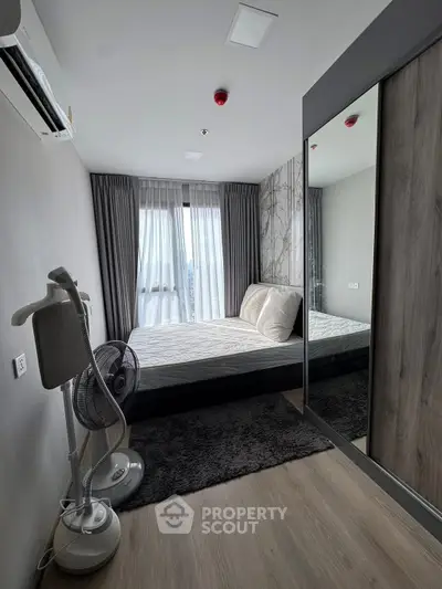 Modern bedroom with large window and stylish decor in a contemporary apartment.