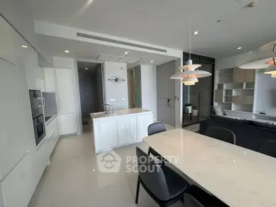 Modern open-plan kitchen and dining area with sleek design and elegant lighting.