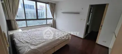 Spacious bedroom with large window and wooden flooring in modern apartment.