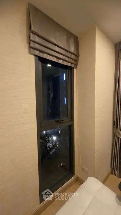 Cozy bedroom with elegant window drapes and night view, perfect for relaxation.