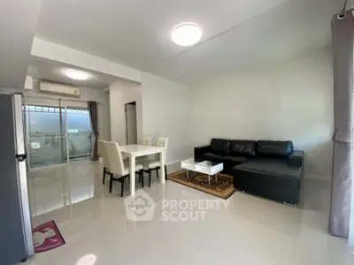 Spacious modern living room with sleek furniture and dining area, featuring large windows for natural light.