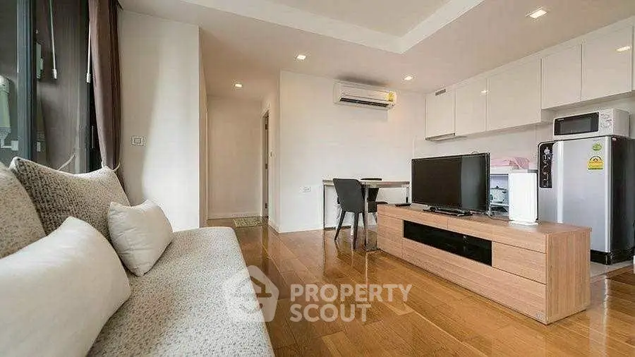Modern living room with sleek furniture and wooden flooring, featuring a cozy sofa and entertainment unit.