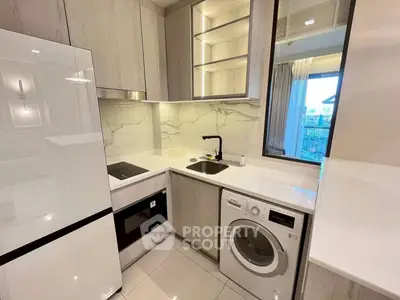 Modern compact kitchen with sleek appliances and stylish cabinetry in a contemporary apartment.