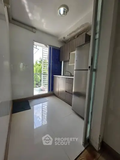 Compact kitchen with modern appliances and balcony access, perfect for urban living.