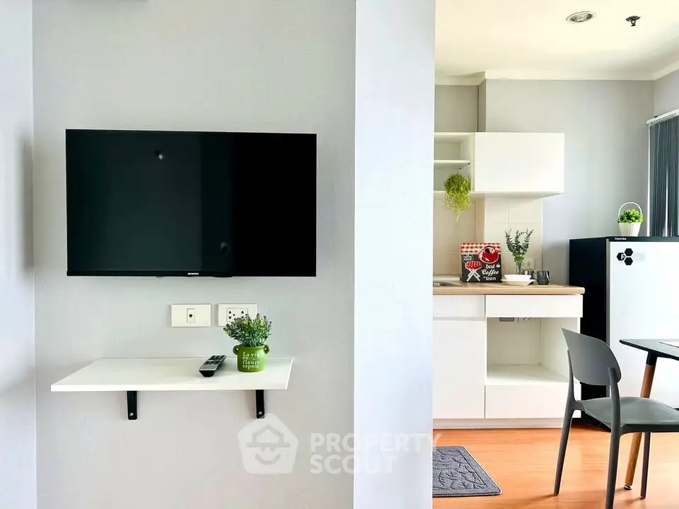 Modern apartment interior with wall-mounted TV and sleek kitchen design.