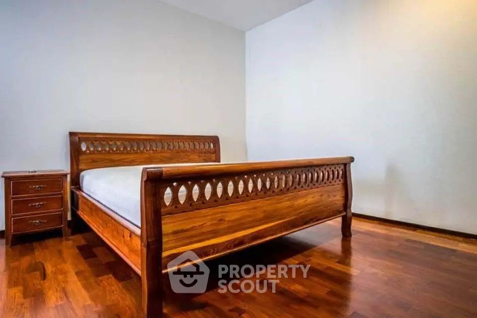 Spacious bedroom with elegant wooden bed and hardwood flooring