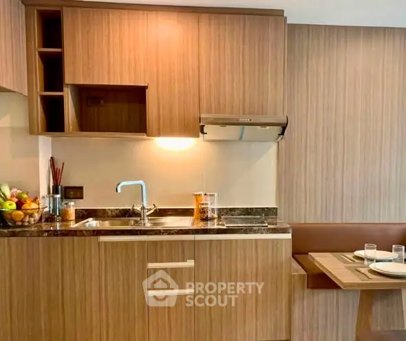 Modern kitchen with wooden cabinetry and cozy dining nook in stylish apartment.