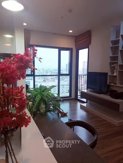 Modern living room with city view, featuring stylish decor and large windows for natural light.